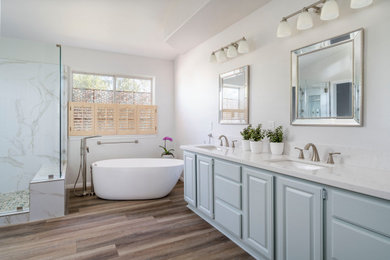 Inspiration for a large contemporary master white tile and porcelain tile vinyl floor, brown floor and double-sink bathroom remodel in Los Angeles with raised-panel cabinets, blue cabinets, a two-piece toilet, gray walls, an undermount sink, quartz countertops, a hinged shower door, white countertops and a built-in vanity