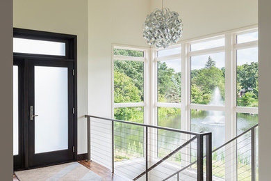 Transitional medium tone wood floor entryway photo in Minneapolis with beige walls and a black front door