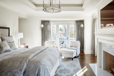 Elegant master brown floor and tray ceiling bedroom photo in Other with a stone fireplace
