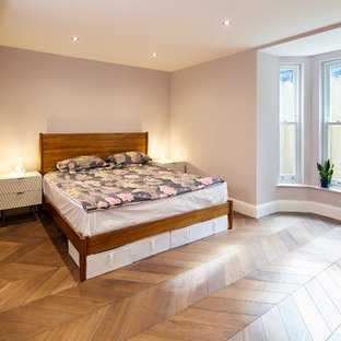 Inspiration for a small contemporary look-out basement in London with pink walls, light hardwood flooring, no fireplace and brown floors.