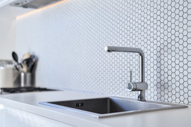 Design ideas for a medium sized modern galley kitchen/diner in London with a single-bowl sink, flat-panel cabinets, white cabinets, laminate countertops, white splashback, ceramic splashback, stainless steel appliances, lino flooring, no island, grey floors and white worktops.