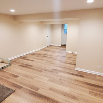 Fully remodeled 1970s finished basement with luxury vinyl plank flooring and can