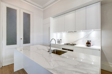 Photo of a large contemporary galley open plan kitchen in Bordeaux with an undermount sink, beaded inset cabinets, white cabinets, marble benchtops, white splashback, marble splashback, stainless steel appliances, with island and white benchtop.
