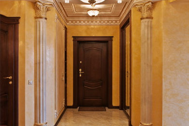 Modelo de hall clásico grande con paredes amarillas, suelo de madera en tonos medios, puerta simple, puerta marrón y suelo marrón