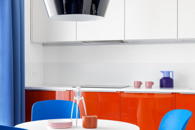 Mid-sized contemporary single-wall eat-in kitchen in Moscow with an undermount sink, flat-panel cabinets, orange cabinets, solid surface benchtops, white splashback, stone slab splashback, white appliances, porcelain floors, no island, brown floor and white benchtop.
