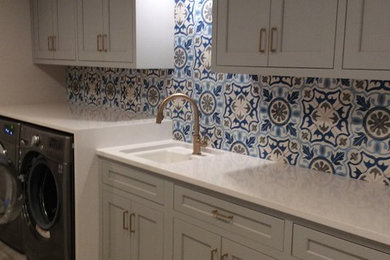 Laundry room - large mediterranean vinyl floor laundry room idea in Baltimore with an undermount sink, shaker cabinets, gray cabinets, quartz countertops, a side-by-side washer/dryer and white countertops