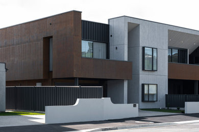 Photo of a mid-sized industrial two-storey concrete black townhouse exterior in Hobart with a flat roof, a metal roof, a black roof and board and batten siding.