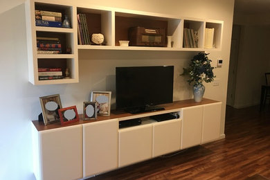 Mid-sized trendy open concept medium tone wood floor and brown floor living room photo in New York with white walls and a media wall