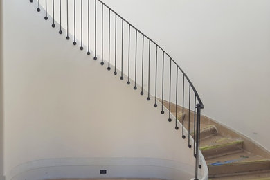 Ejemplo de escalera curva contemporánea con barandilla de metal