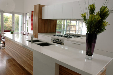 Contemporary l-shaped eat-in kitchen in Melbourne with a double-bowl sink, flat-panel cabinets, white cabinets, quartz benchtops, mirror splashback, stainless steel appliances and with island.