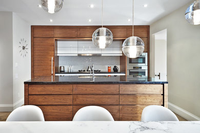 Design ideas for a large midcentury single-wall open plan kitchen in Miami with a drop-in sink, flat-panel cabinets, medium wood cabinets, granite benchtops, white splashback, glass tile splashback, stainless steel appliances, medium hardwood floors, with island and brown floor.