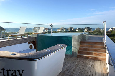 Modern rooftop rectangular infinity pool in Other with decking.