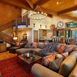 Geräumiges, Offenes Mediterranes Wohnzimmer mit oranger Wandfarbe, braunem Holzboden, Kamin, Kaminsims aus Stein und Multimediawand in Salt Lake City