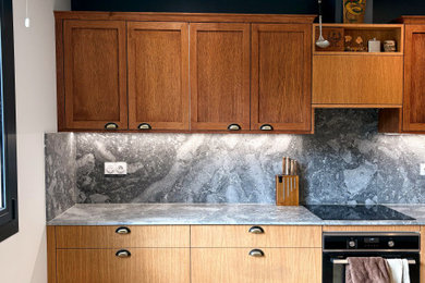 Idée de décoration pour une grande cuisine ouverte bicolore champêtre en L et bois clair avec un évier encastré, un placard avec porte à panneau encastré, un plan de travail en granite, une crédence grise, une crédence en granite, un électroménager en acier inoxydable, un sol en travertin, aucun îlot, un sol beige et un plan de travail gris.