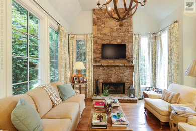 Example of a mid-sized open concept medium tone wood floor and tray ceiling family room design in San Francisco with white walls, a standard fireplace, a stacked stone fireplace and a wall-mounted tv