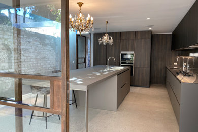 This is an example of a mid-sized modern l-shaped open plan kitchen in Sydney with an undermount sink, raised-panel cabinets, dark wood cabinets, laminate benchtops, metallic splashback, metal splashback, panelled appliances, concrete floors, with island, grey floor and grey benchtop.