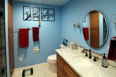 Example of a mid-sized multicolored tile and porcelain tile porcelain tile, white floor and single-sink bathroom design in San Francisco with raised-panel cabinets, medium tone wood cabinets, a two-piece toilet, blue walls, an undermount sink, quartz countertops, a hinged shower door, white countertops, a niche and a built-in vanity