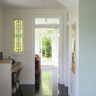 Bild på en vintage hall, med beige väggar och svart golv