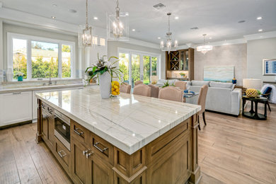 Transitional brown floor and medium tone wood floor open concept kitchen photo in Los Angeles with shaker cabinets, medium tone wood cabinets, marble countertops, an island, multicolored countertops, an undermount sink, multicolored backsplash, mosaic tile backsplash and stainless steel appliances