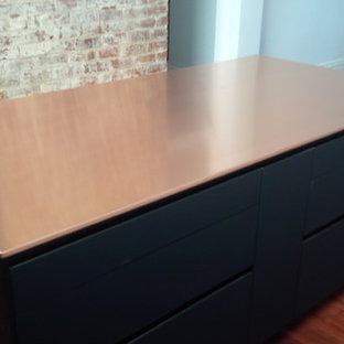 Einzeilige, Mittelgroße Industrial Küche mit Vorratsschrank, Waschbecken, schwarzen Schränken, Kupfer-Arbeitsplatte, Küchenrückwand in Metallic, Glasrückwand, schwarzen Elektrogeräten, braunem Holzboden und Kücheninsel in Perth