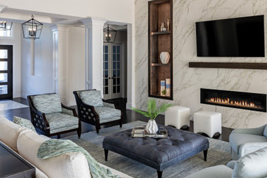 Example of a large transitional open concept dark wood floor, brown floor and exposed beam living room design with beige walls, a standard fireplace, a stone fireplace and a media wall