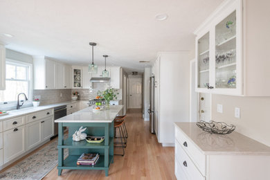 Example of a large transitional galley light wood floor and brown floor eat-in kitchen design in Boston with an undermount sink, shaker cabinets, white cabinets, quartz countertops, beige backsplash, ceramic backsplash, stainless steel appliances, an island and white countertops