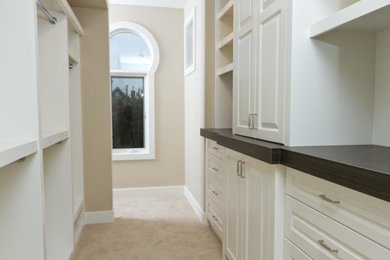 Inspiration for a mid-sized transitional gender-neutral carpeted and beige floor walk-in closet remodel in Calgary with raised-panel cabinets and white cabinets