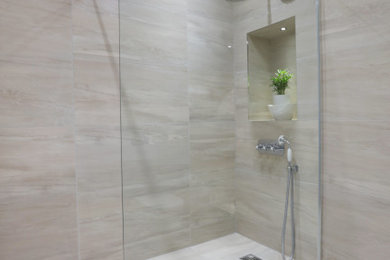 Large traditional kids bathroom in Edinburgh with glass-front cabinets, white cabinets, an open shower, a wall-mount toilet, beige tile, porcelain tile, beige walls, porcelain floors, an undermount sink, marble benchtops, beige floor, an open shower, black benchtops, a niche, a single vanity and a freestanding vanity.