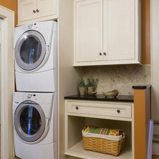 Traditional utility room in New York with orange walls and a stacked washer and dryer.