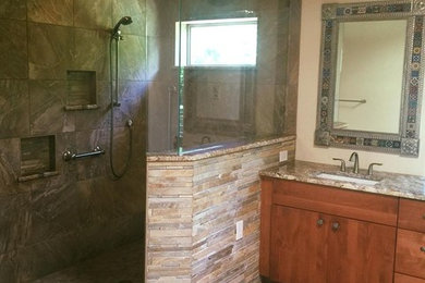 Inspiration for a mid-sized rustic master beige tile, white tile and stone slab light wood floor bathroom remodel in Albuquerque with flat-panel cabinets, medium tone wood cabinets, a one-piece toilet, beige walls, a drop-in sink and solid surface countertops