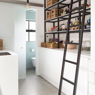 Exemple d'une petite arrière-cuisine parallèle tendance avec un placard à porte plane, des portes de placard blanches, une crédence blanche, une crédence en carrelage métro, un plan de travail en surface solide, béton au sol et aucun îlot.