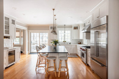 Example of a large transitional u-shaped medium tone wood floor and brown floor eat-in kitchen design in Boston with an undermount sink, shaker cabinets, white cabinets, quartz countertops, gray backsplash, subway tile backsplash, stainless steel appliances, an island and black countertops