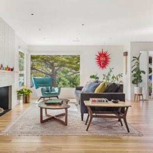 Example of a mid-century modern light wood floor and brown floor living room design in San Francisco with white walls, a standard fireplace and a brick fireplace