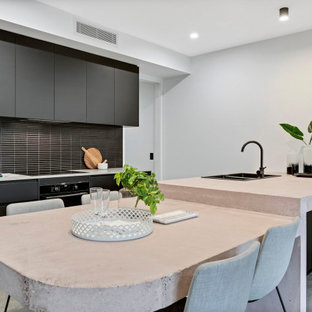 Design ideas for a contemporary kitchen in Sunshine Coast with a double-bowl sink, flat-panel cabinets, black cabinets, black splashback, matchstick tile splashback, black appliances, a peninsula, grey floor and beige benchtop.