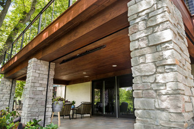 Réalisation d'un porche d'entrée de maison arrière tradition avec une moustiquaire, des pavés en béton, une extension de toiture et un garde-corps en matériaux mixtes.