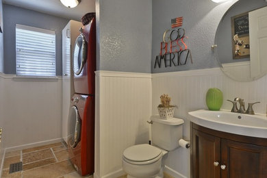 Utility room - small modern galley travertine floor and brown floor utility room idea in Denver with a single-bowl sink, white cabinets, blue walls and a stacked washer/dryer