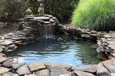 Inspiration for a traditional backyard river rock landscaping in Philadelphia.