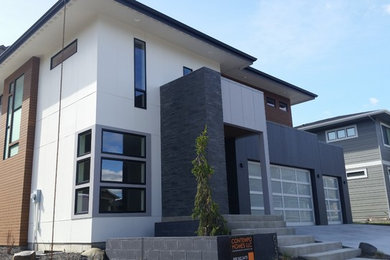 This is an example of a mid-sized contemporary two-storey grey exterior in Seattle with mixed siding and a flat roof.