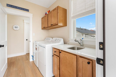 Mid-sized transitional galley dedicated laundry room photo in Philadelphia with an undermount sink, recessed-panel cabinets, light wood cabinets, quartz countertops, a side-by-side washer/dryer and white countertops