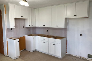 Mid-sized transitional l-shaped eat-in kitchen in Wichita with a farmhouse sink, shaker cabinets, white cabinets and no island.