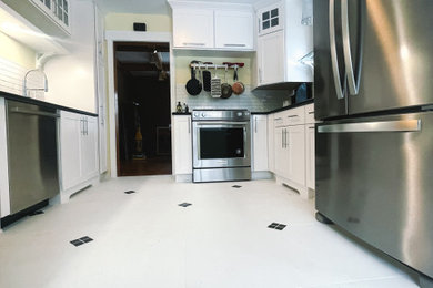 Example of a mid-sized ceramic tile and white floor kitchen design in Other with an undermount sink, white cabinets, quartzite countertops, white backsplash, ceramic backsplash, stainless steel appliances, no island and black countertops