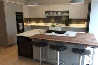 This is an example of a l-shaped open plan kitchen in West Midlands with a belfast sink, marble worktops, glass sheet splashback, an island and white worktops.