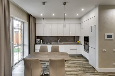 Inspiration for a mid-sized contemporary l-shaped eat-in kitchen in Other with a drop-in sink, flat-panel cabinets, white cabinets, stainless steel appliances, ceramic floors, no island, brown floor, grey splashback and grey benchtop.