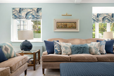 ハンプシャーにある高級な中くらいなトラディショナルスタイルのおしゃれなリビング (青い壁、カーペット敷き、薪ストーブ、レンガの暖炉まわり、コーナー型テレビ、ベージュの床) の写真