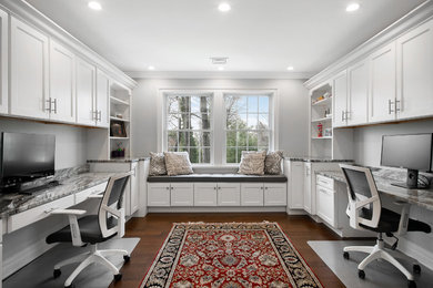 Transitional built-in desk dark wood floor and brown floor home office photo in New York with gray walls