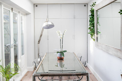 Contemporary enclosed dining room in London with white walls, medium hardwood flooring and brown floors.