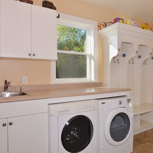 Medium sized classic single-wall utility room in Vancouver with white cabinets, laminate countertops, ceramic flooring, a side by side washer and dryer, a built-in sink, flat-panel cabinets and orange walls.