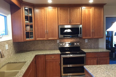 This is an example of a mid-sized traditional l-shaped separate kitchen in Philadelphia with a double-bowl sink, recessed-panel cabinets, medium wood cabinets, granite benchtops, beige splashback, porcelain splashback, stainless steel appliances, light hardwood floors, with island and beige floor.