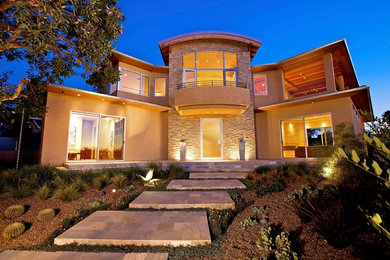 Large minimalist beige two-story stucco house exterior photo in San Diego with a hip roof