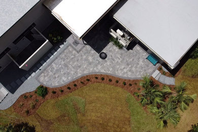 Example of a large minimalist backyard concrete paver patio design in Other